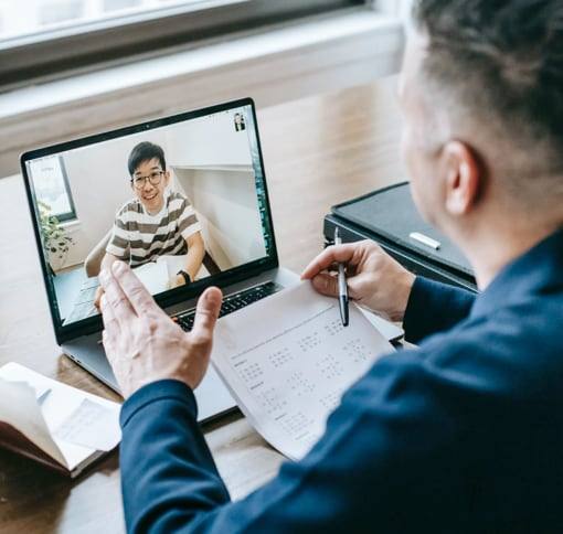 A man in a video meeting with a colleague on his laptop.