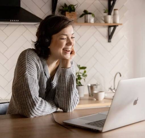 A woman smiling at her laptop during a video call.